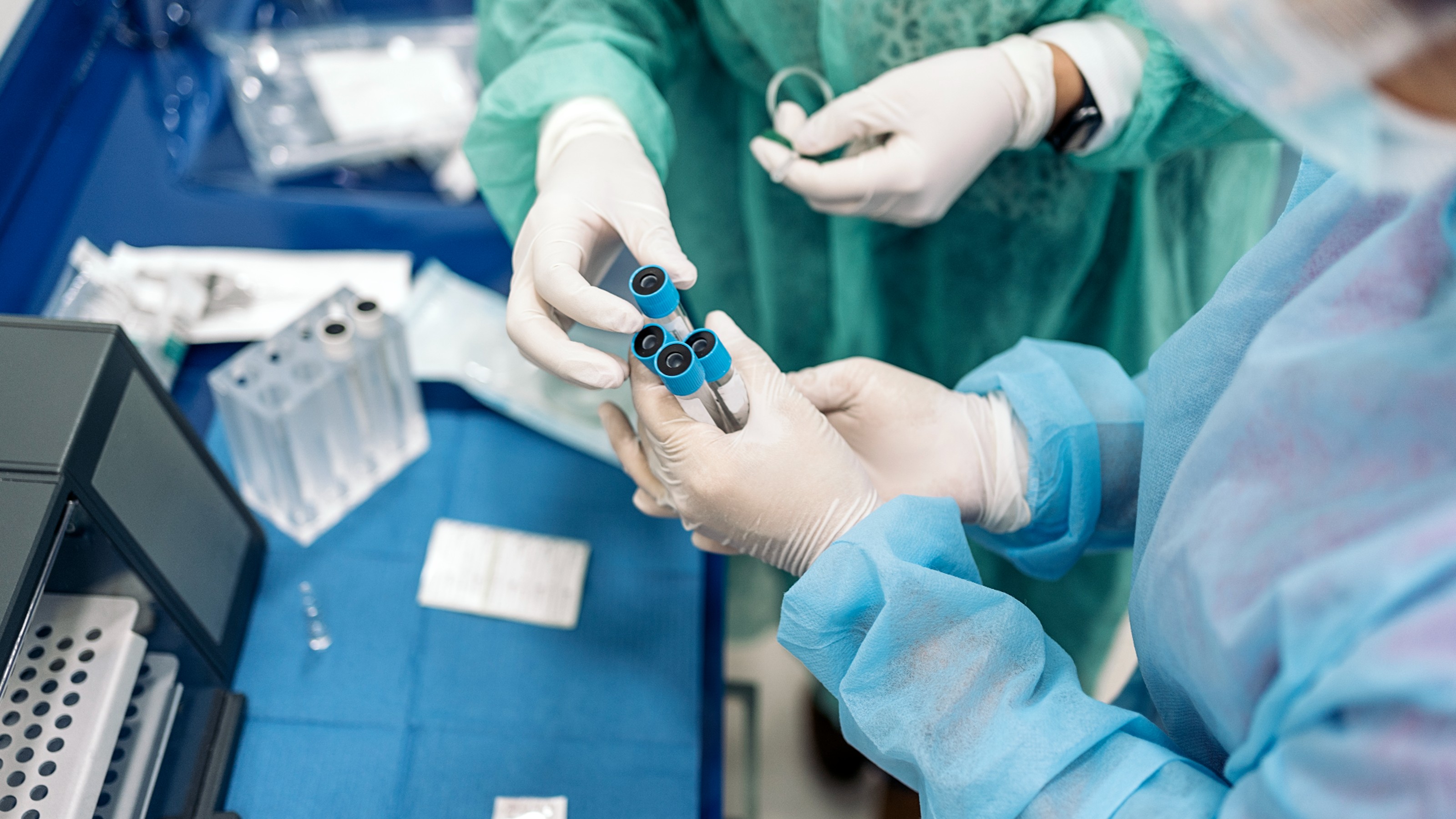 Professionals medic workers wearing latex gloves looking at sample tubes in the lab.