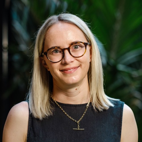 Woman with blonde hair and glasses smiling.
