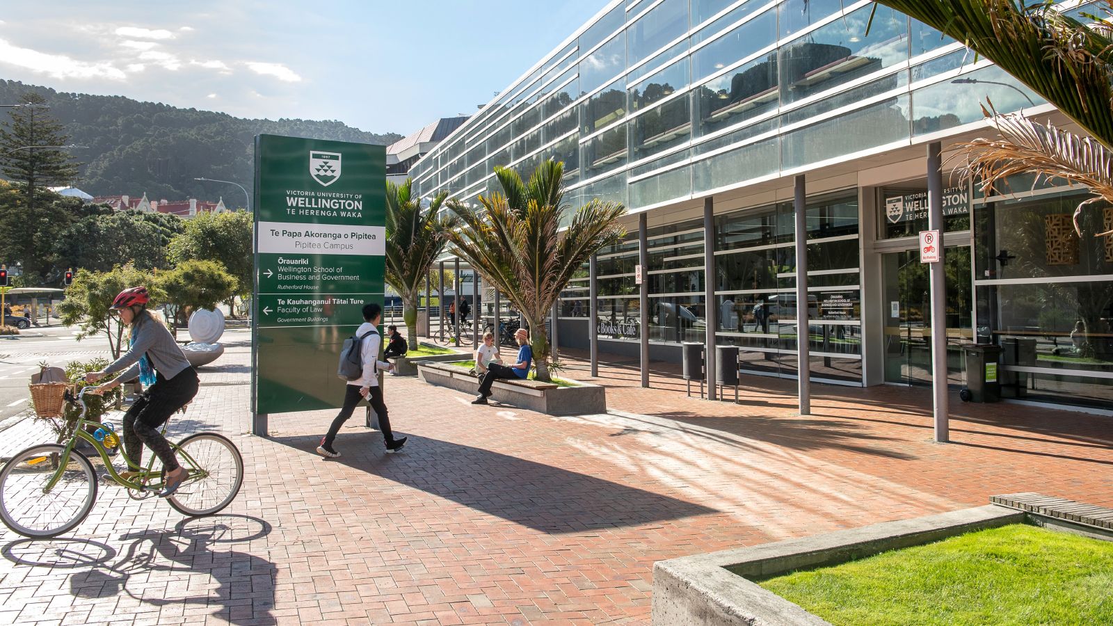 Woman on a bike and a man walking into a building