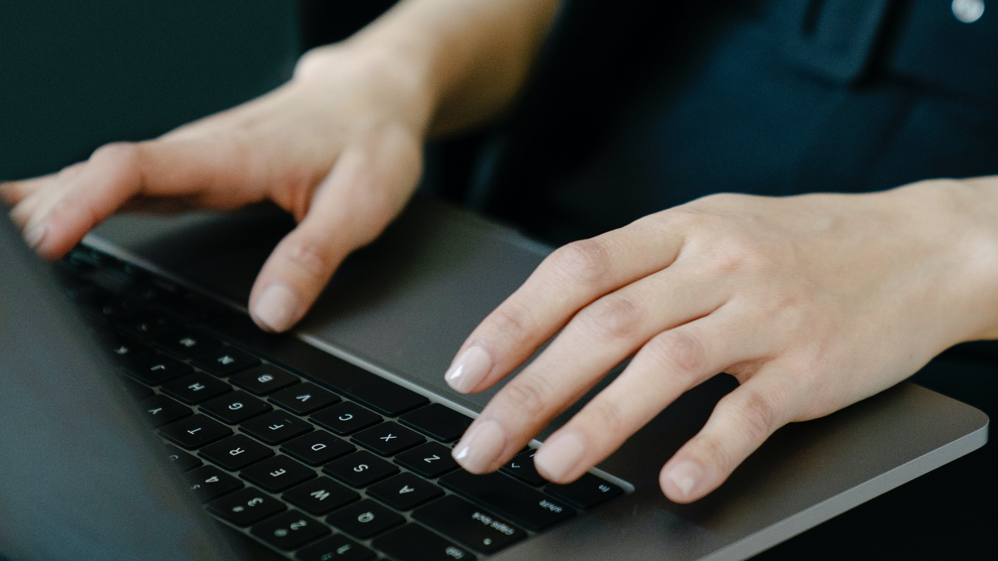 Someone typing on a keyboard with just their hands visible in the image