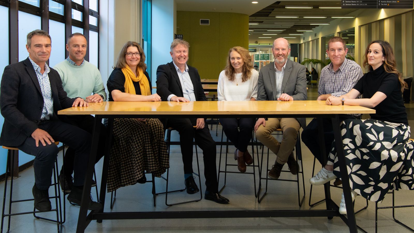 A group of eight people sitting behind a table.