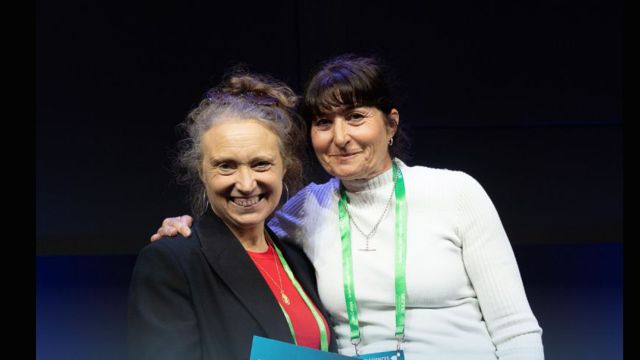 Two women smiling at a prize giving ceremony.