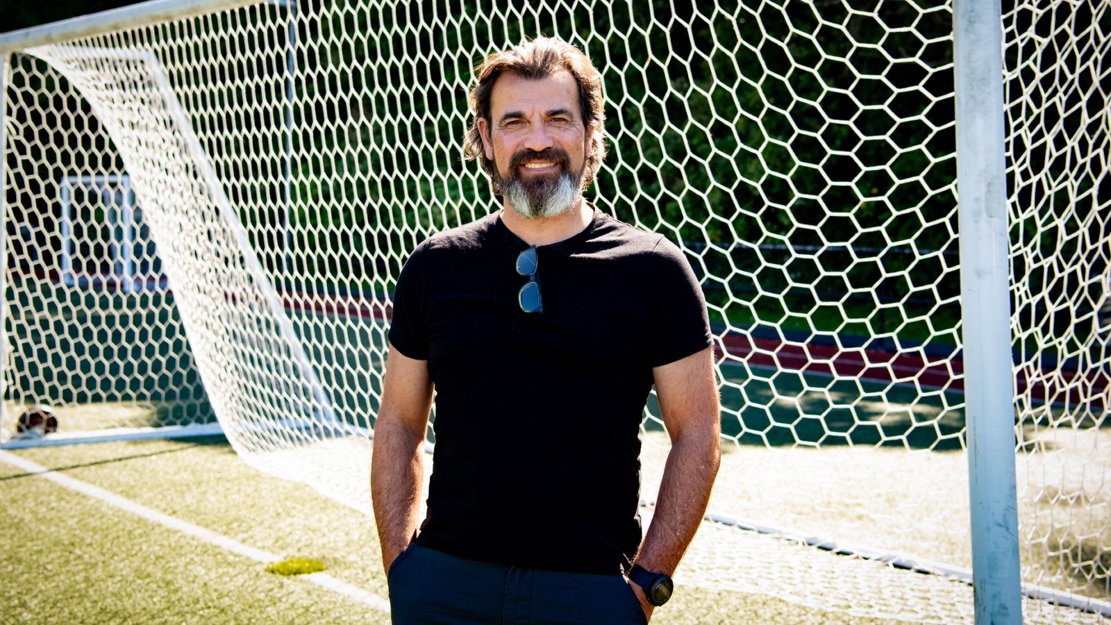 Geoff Kira poses for a photo in front of a football net.