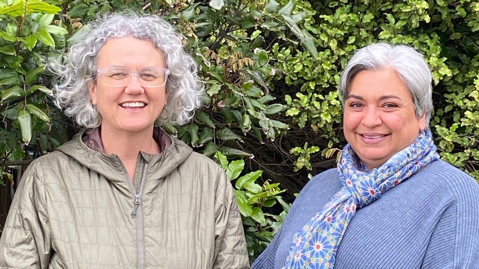 Mona Jeffreys and Kahurangi Dey smiling in front of a hedge