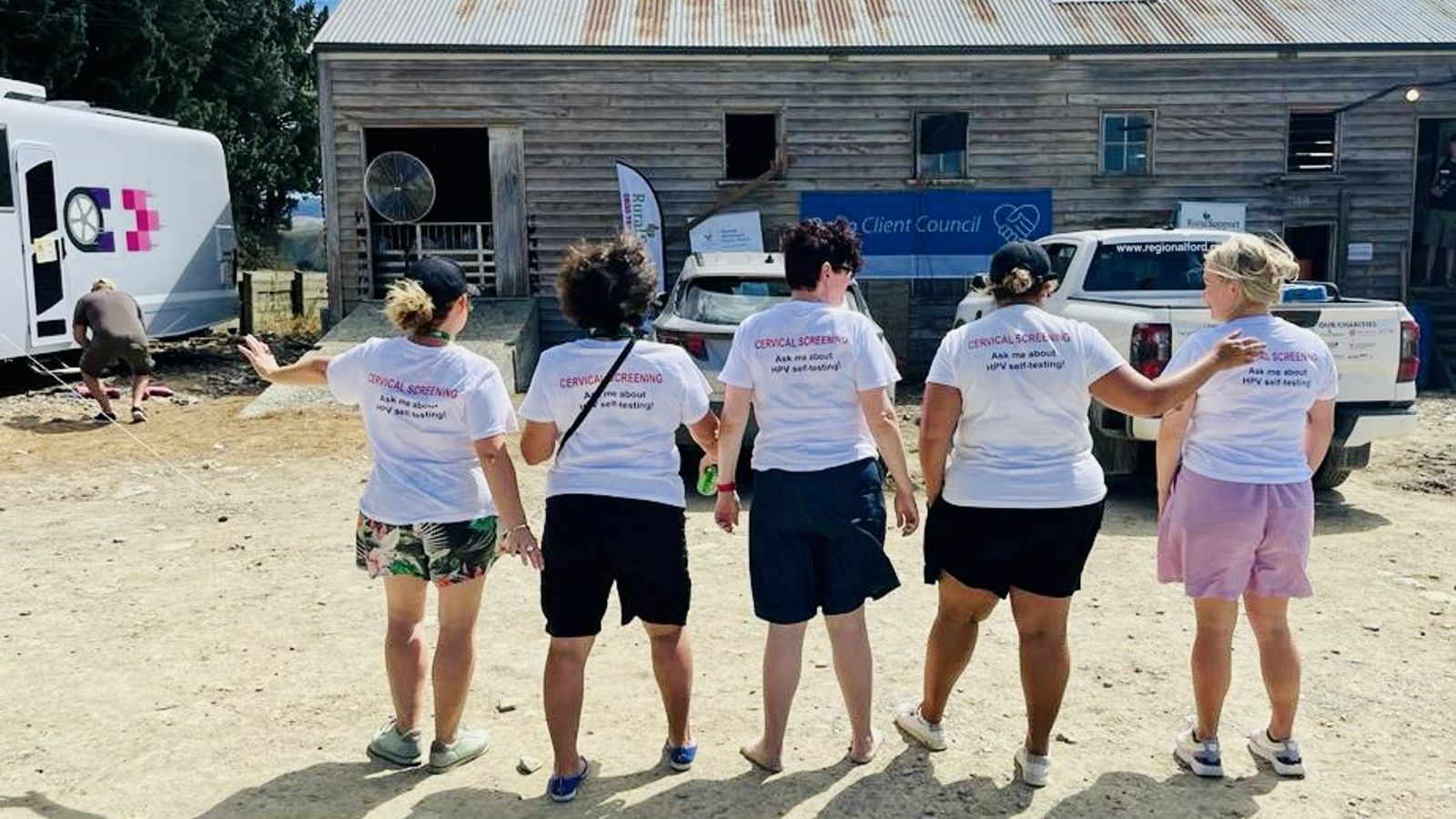 Five of the cervical screening team posing with their back facing the camera. Their t-shirts say ask me about hpv self-testing.