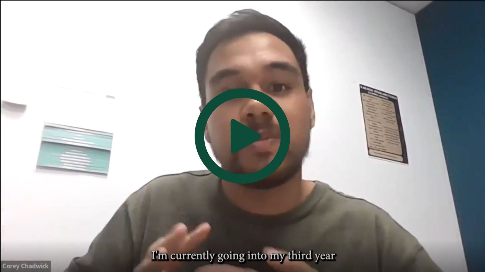 A screenshot of Corey on a Zoom interview with a play button overlaid