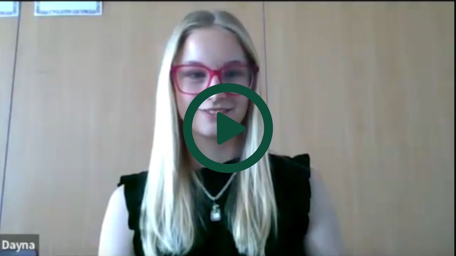 A screenshot of Dayna on a Zoom interview with a play button overlaid