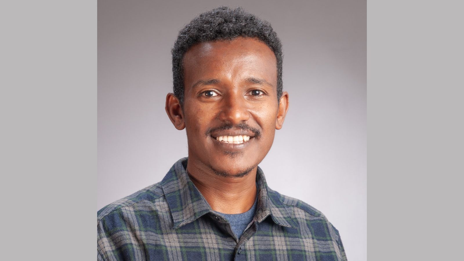 A portrait of Dessalegn smiling into the camera