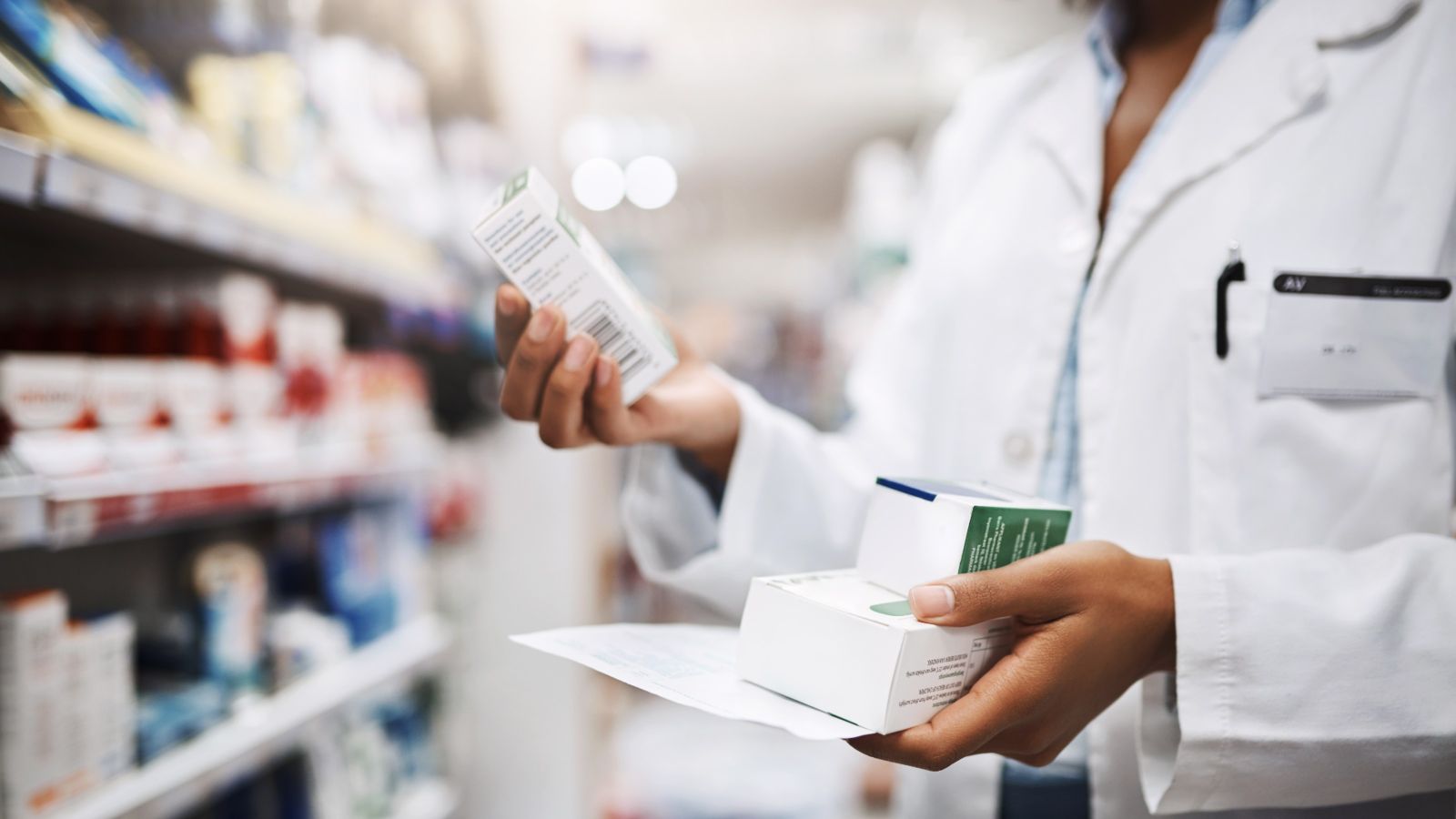 Unrecognisable pharmacist holding a container of medicine.