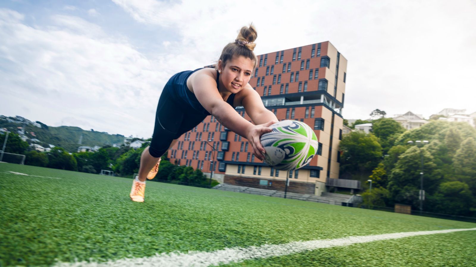 A young woman scoring a try on a field