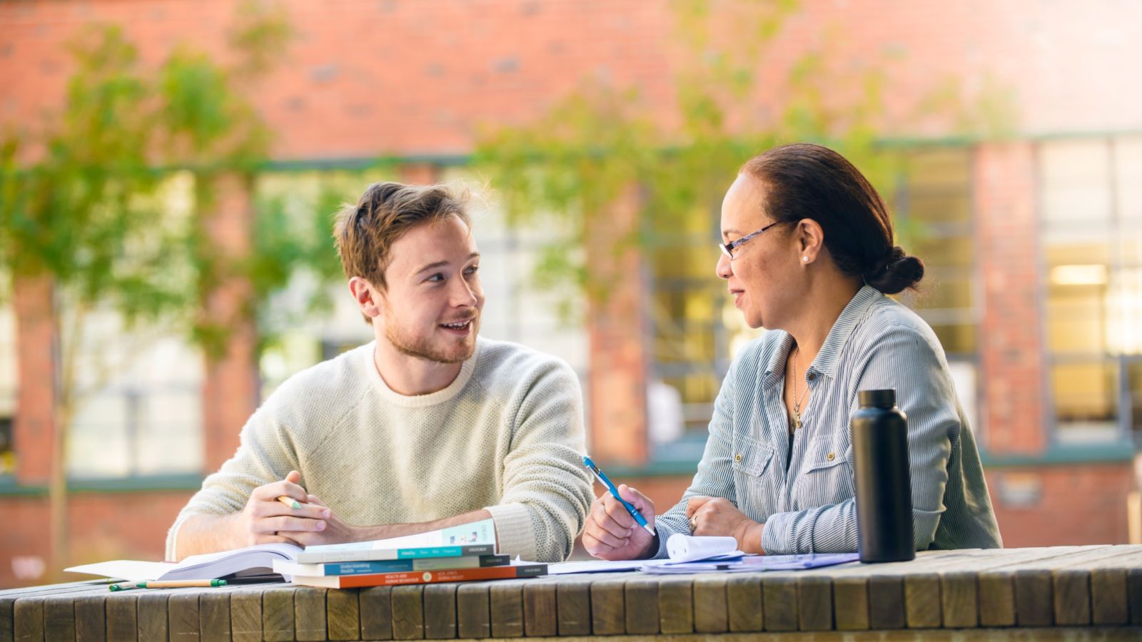 Two students sitting at an outdoor table studying