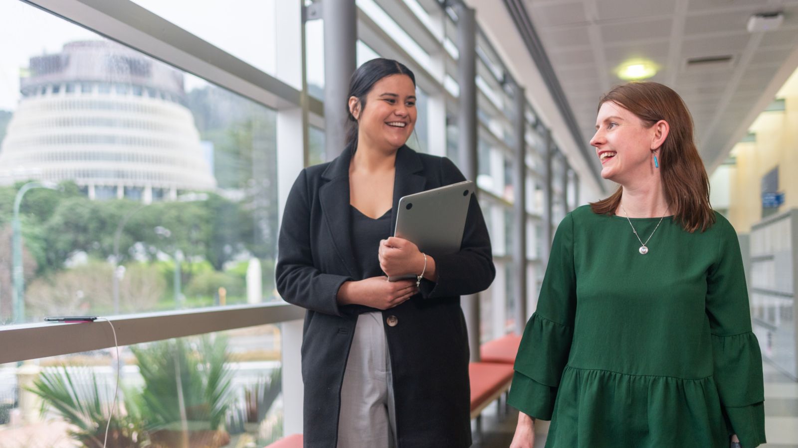 Two students walking through the university with the beehive in the background