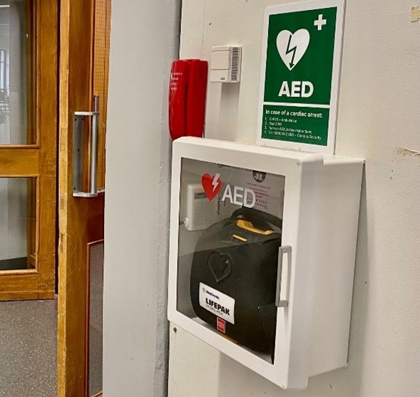 Green AED sign above a glass cabinet with an AED inside