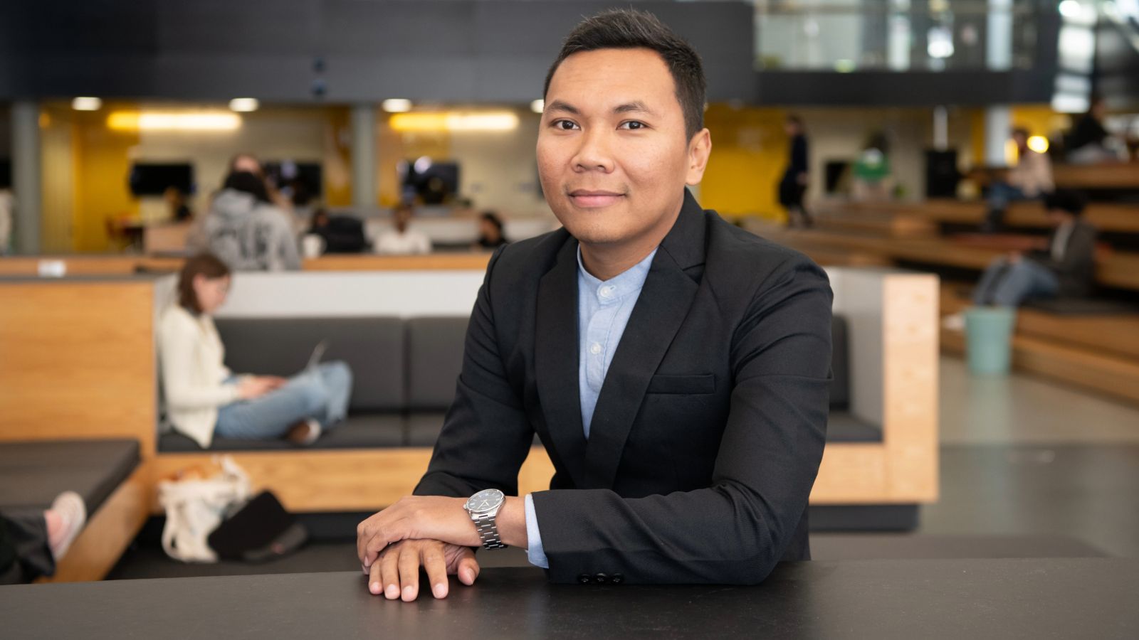Satria sitting at a high table looking into the camera.