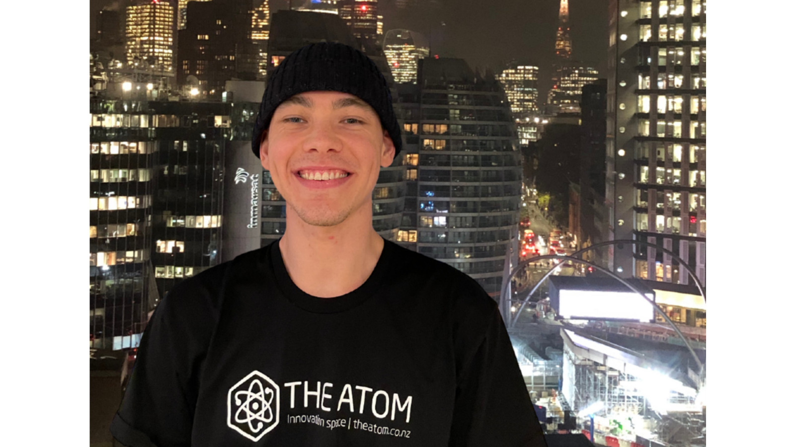 Man in black beanie and hoodie with night city background