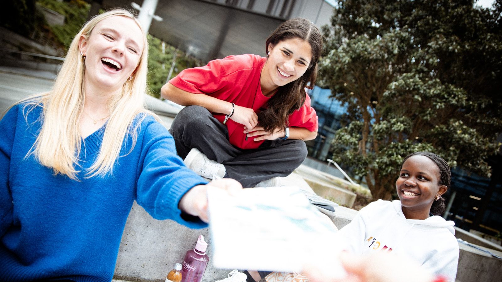 Three students studying at the Cotton Building courtyard