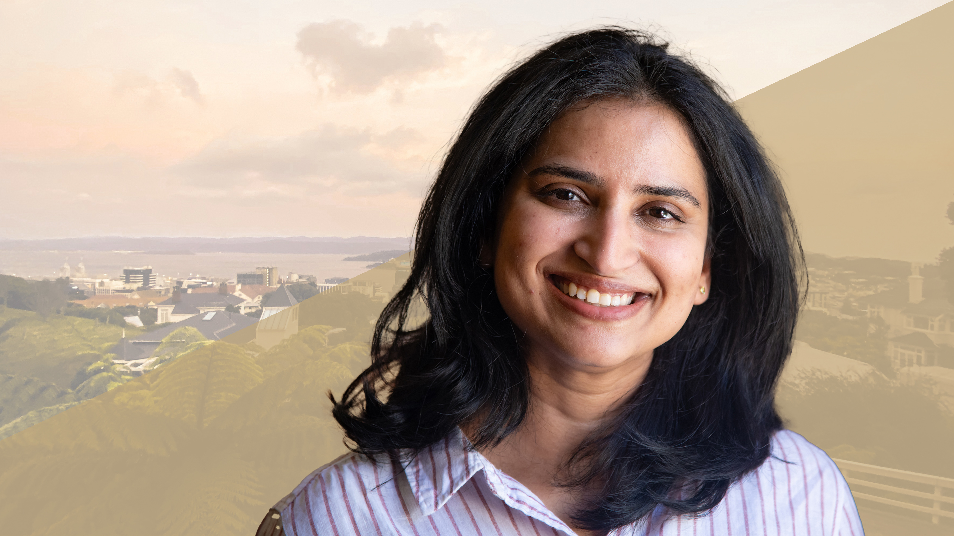 A profile of a woman smiling and wearing a striped shirt.