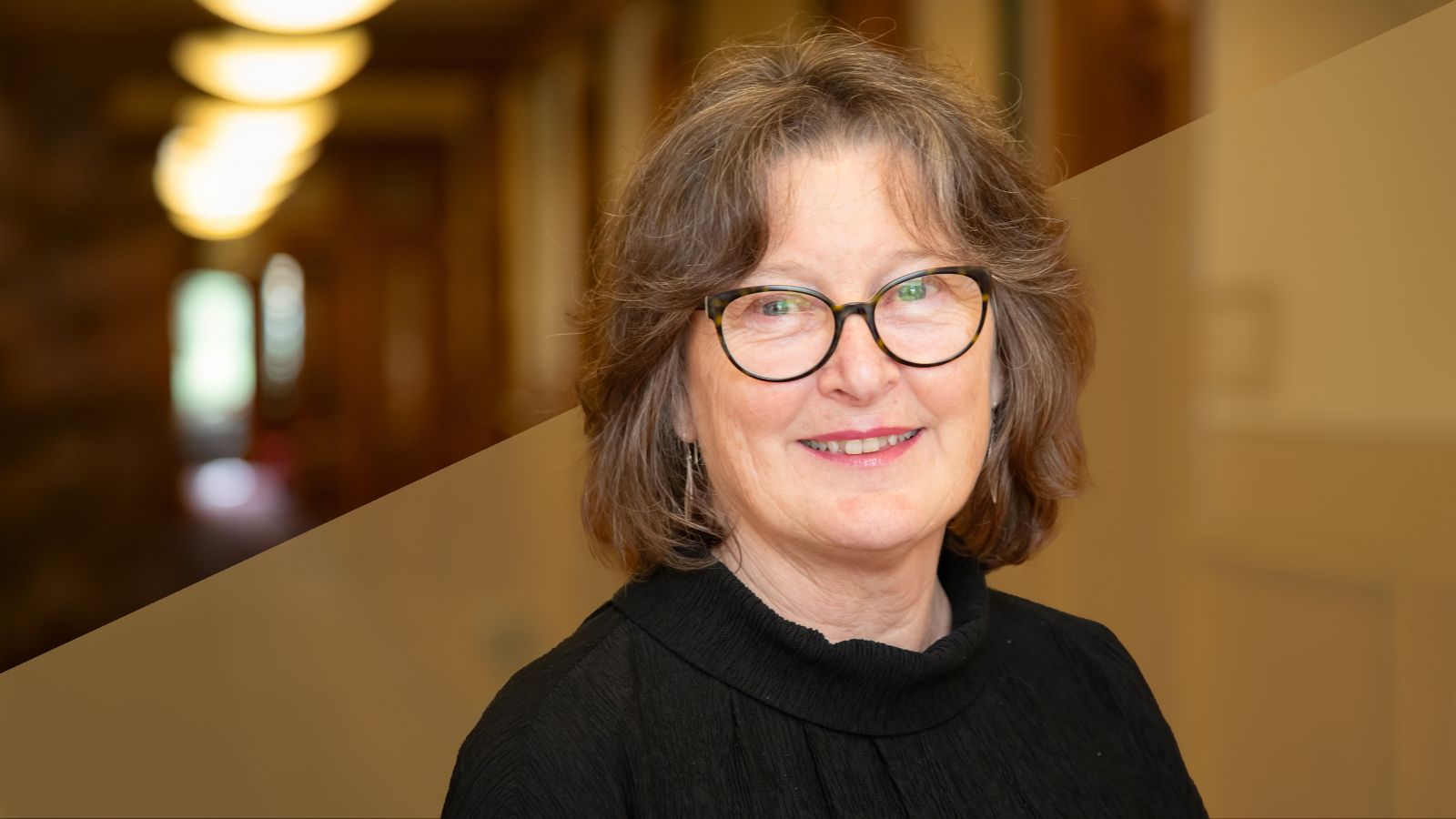 A profile of a woman smiling and wearing glasses and a black shirt.
