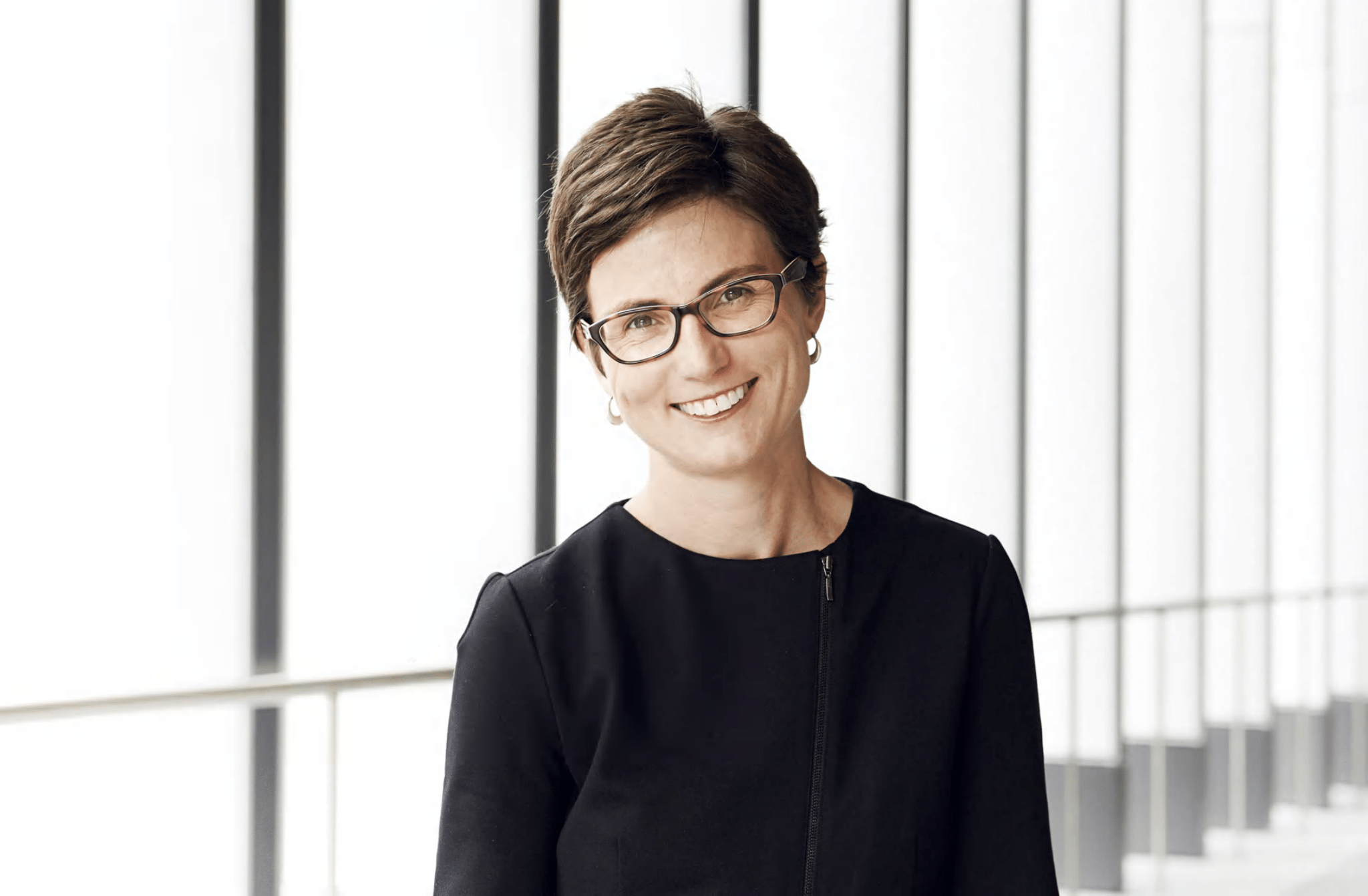 A smiling woman with short hair and glasses. 