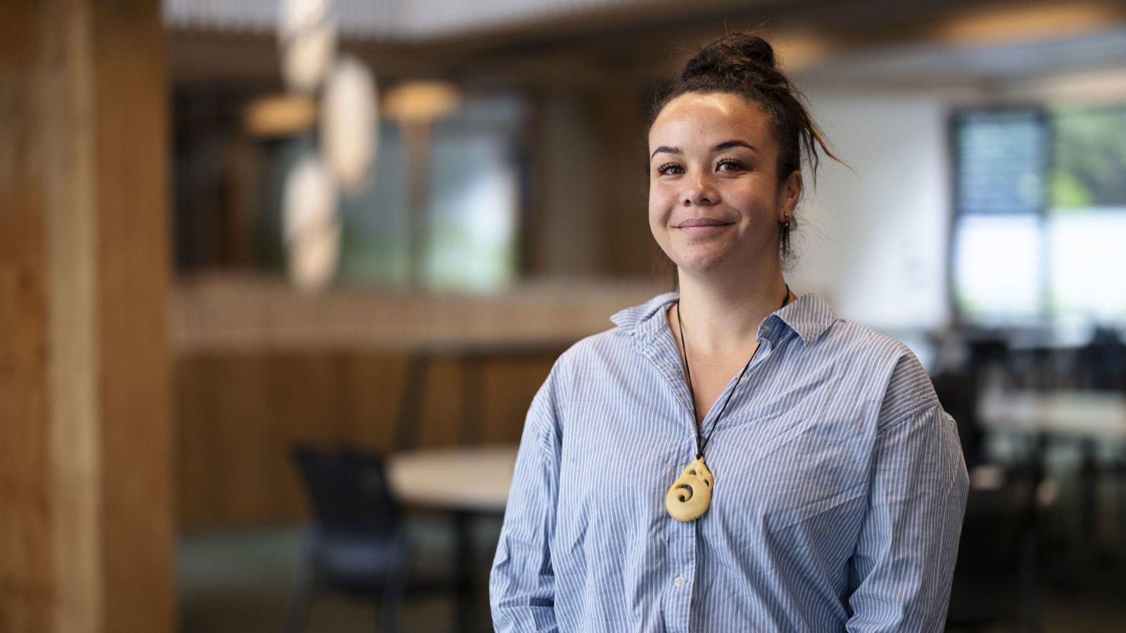Woman wearing blue shirt and carving, slight smile.