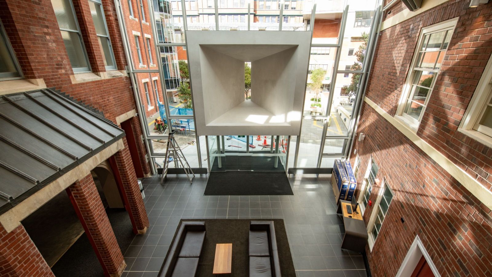 brick clad interior of building with square concrete feature at centre