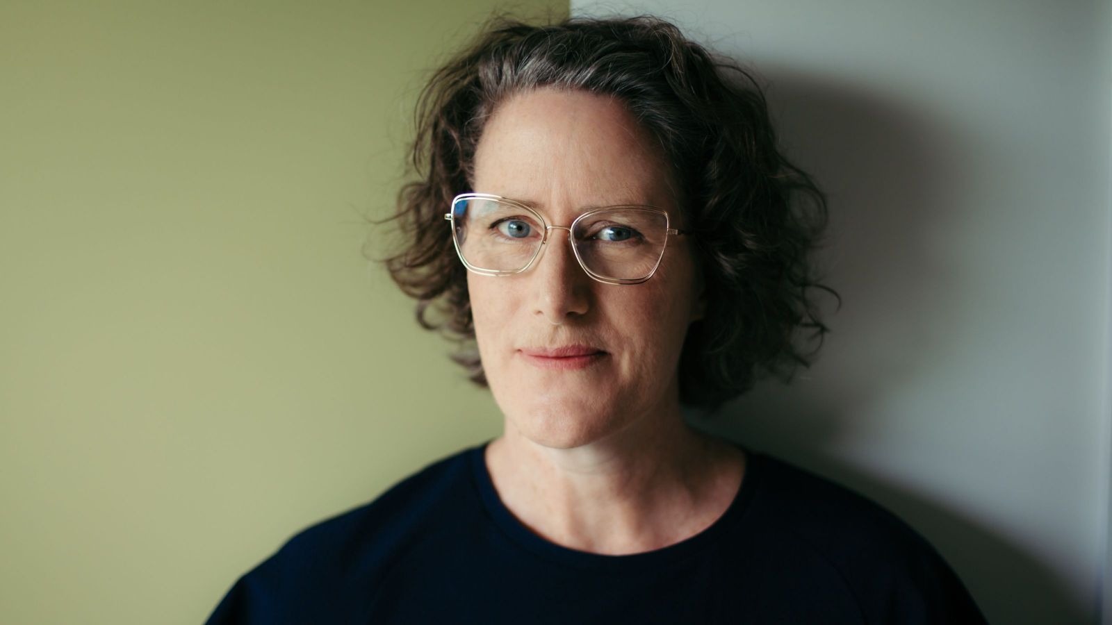 Woman with curly shoulder-length hair against grey background