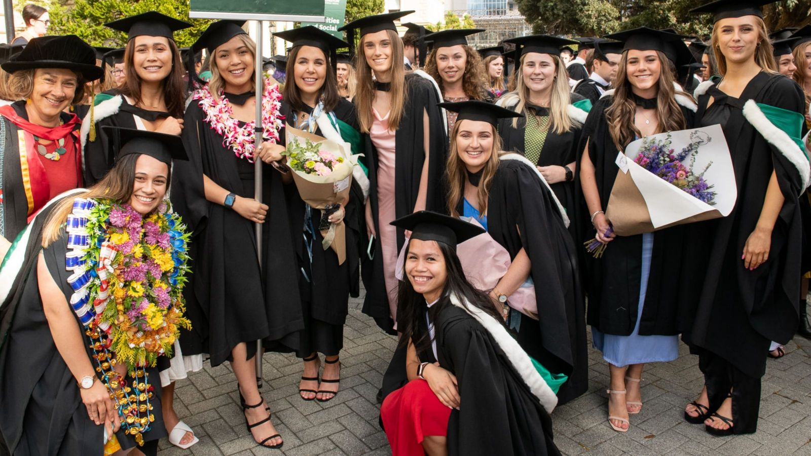 group of girls wearing bachelor of nursing hoods and gowns gathered for graduation