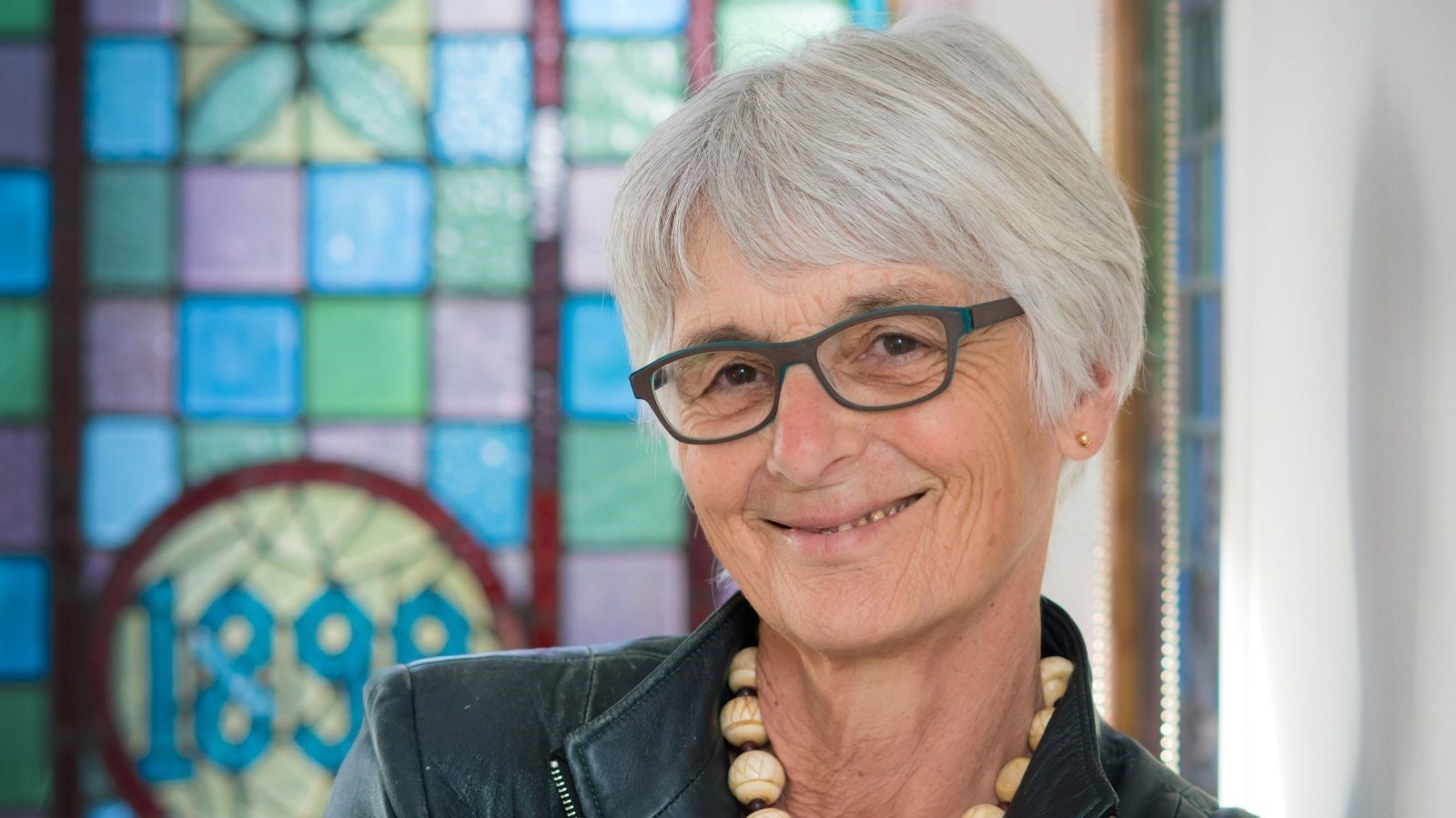 woman smiling with coloured stained class window in back