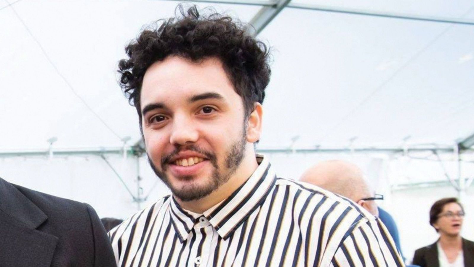 man with curly hair and stripy black and white top