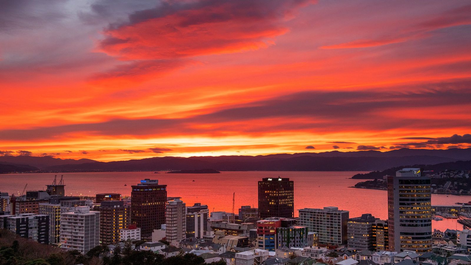 city with buildings with sun rising over mountains