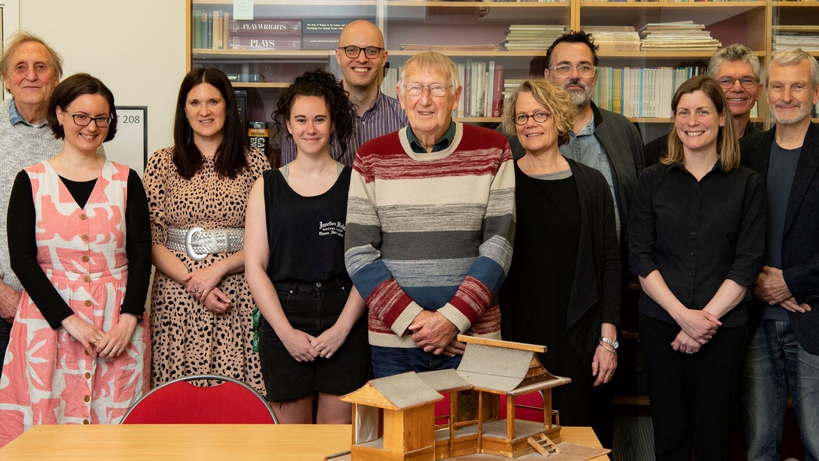 group of 10 people standing with a model in front of them