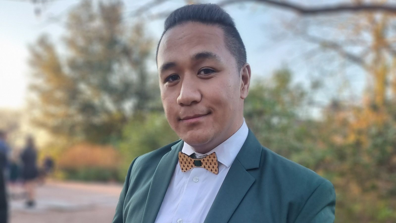 man wearing green suit and wooden bowtie looking at camera