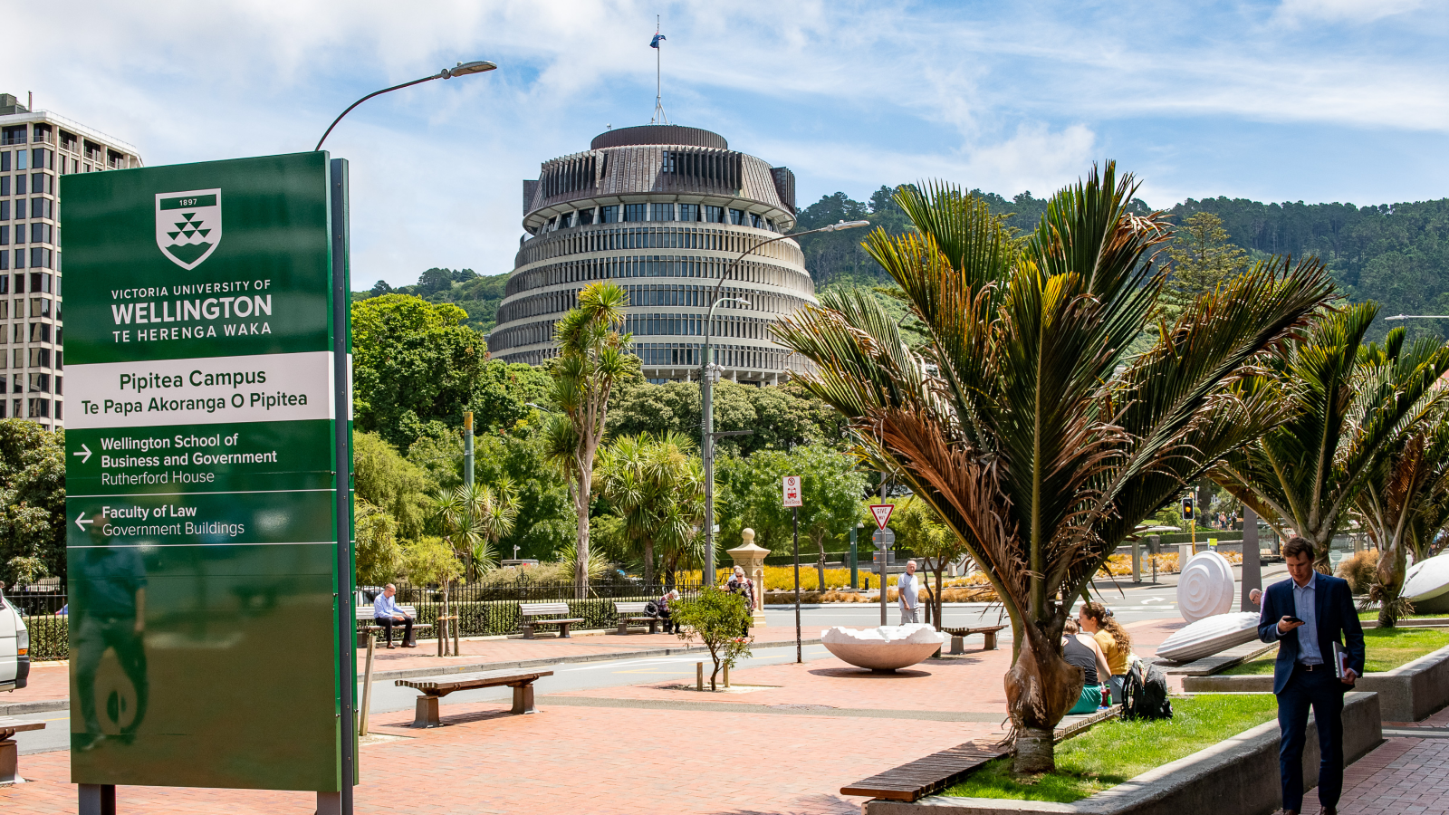 A busy inner-city footpath outside the University's business school, with New Zealand's government buildings in the background.