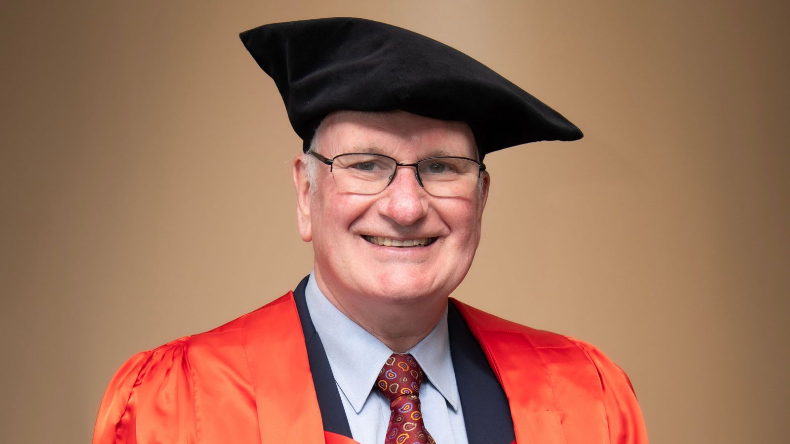 man with scotch bonnet and red robes smiling