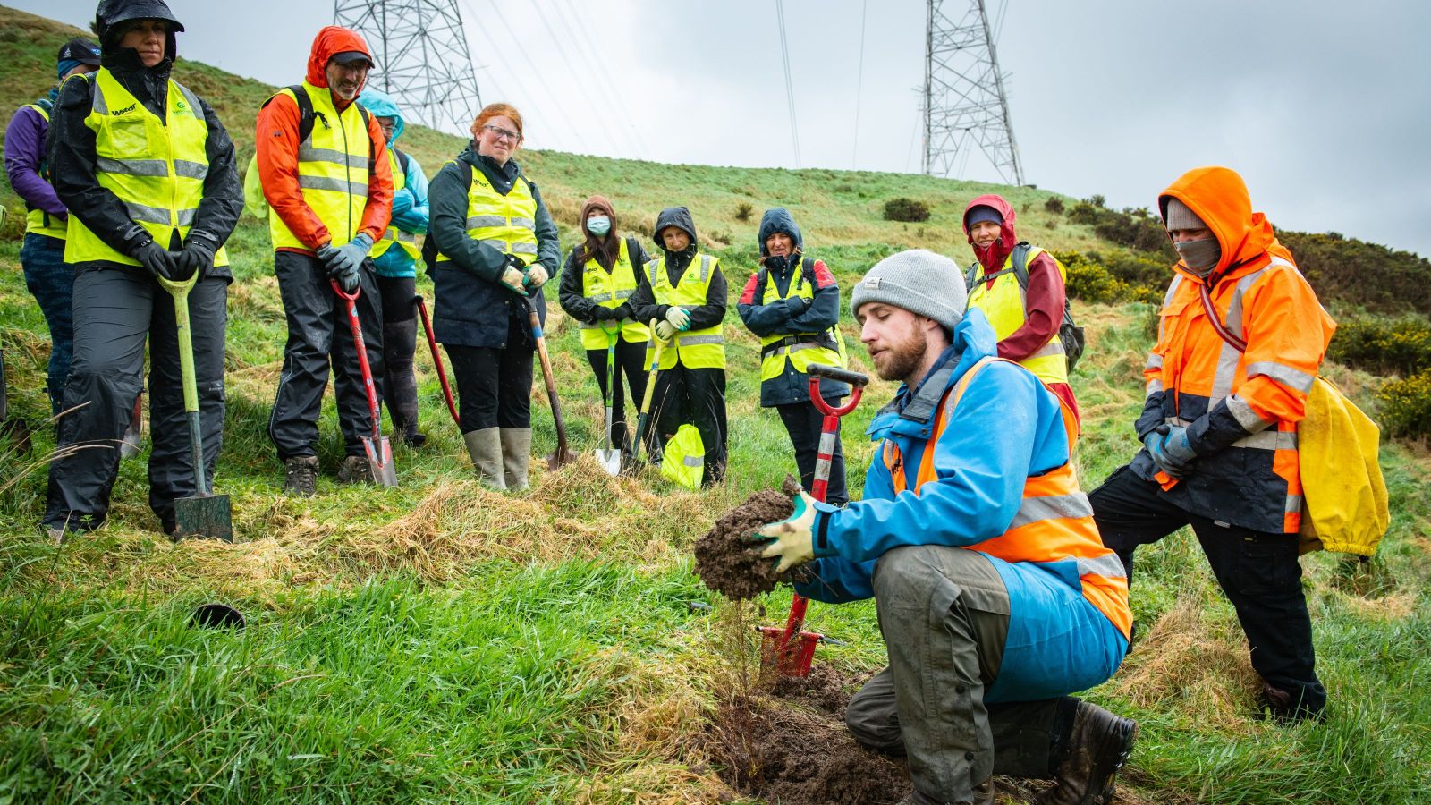 group of people with spades listening to the experts about how to dig plants