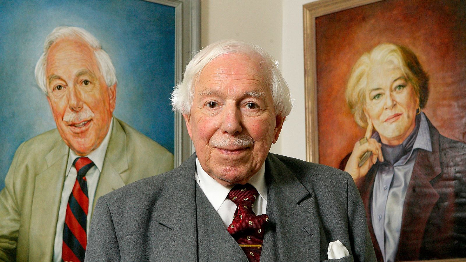 Denis Adam standing in front of portraits