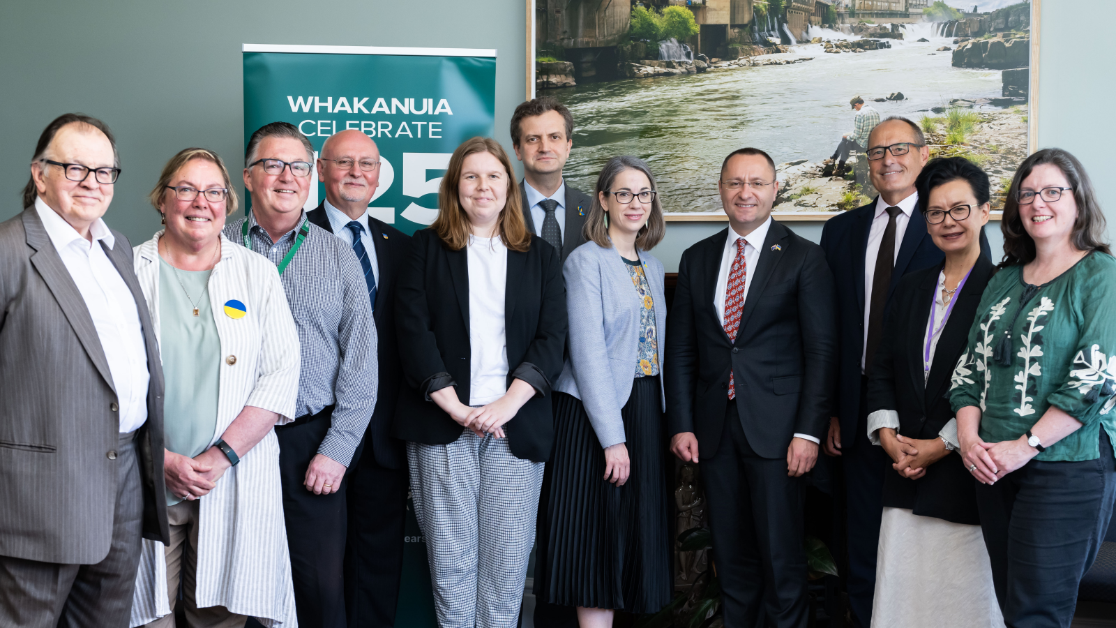 A group of well-dressed people stand smiling in a well-appointed room.