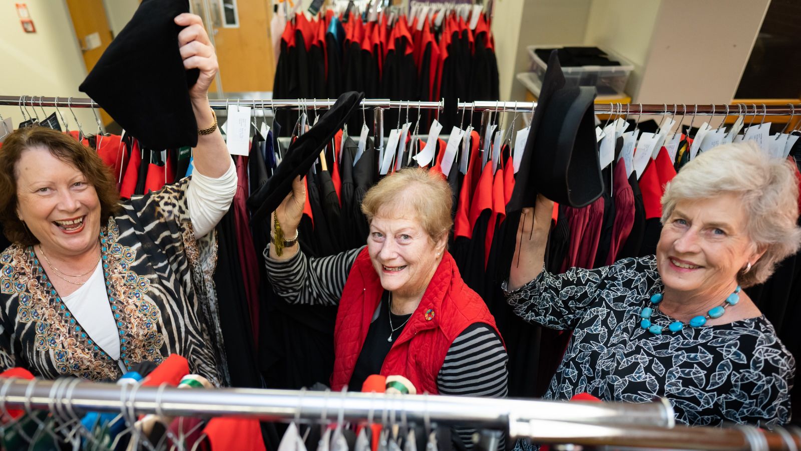women surrounded by graduation gowns