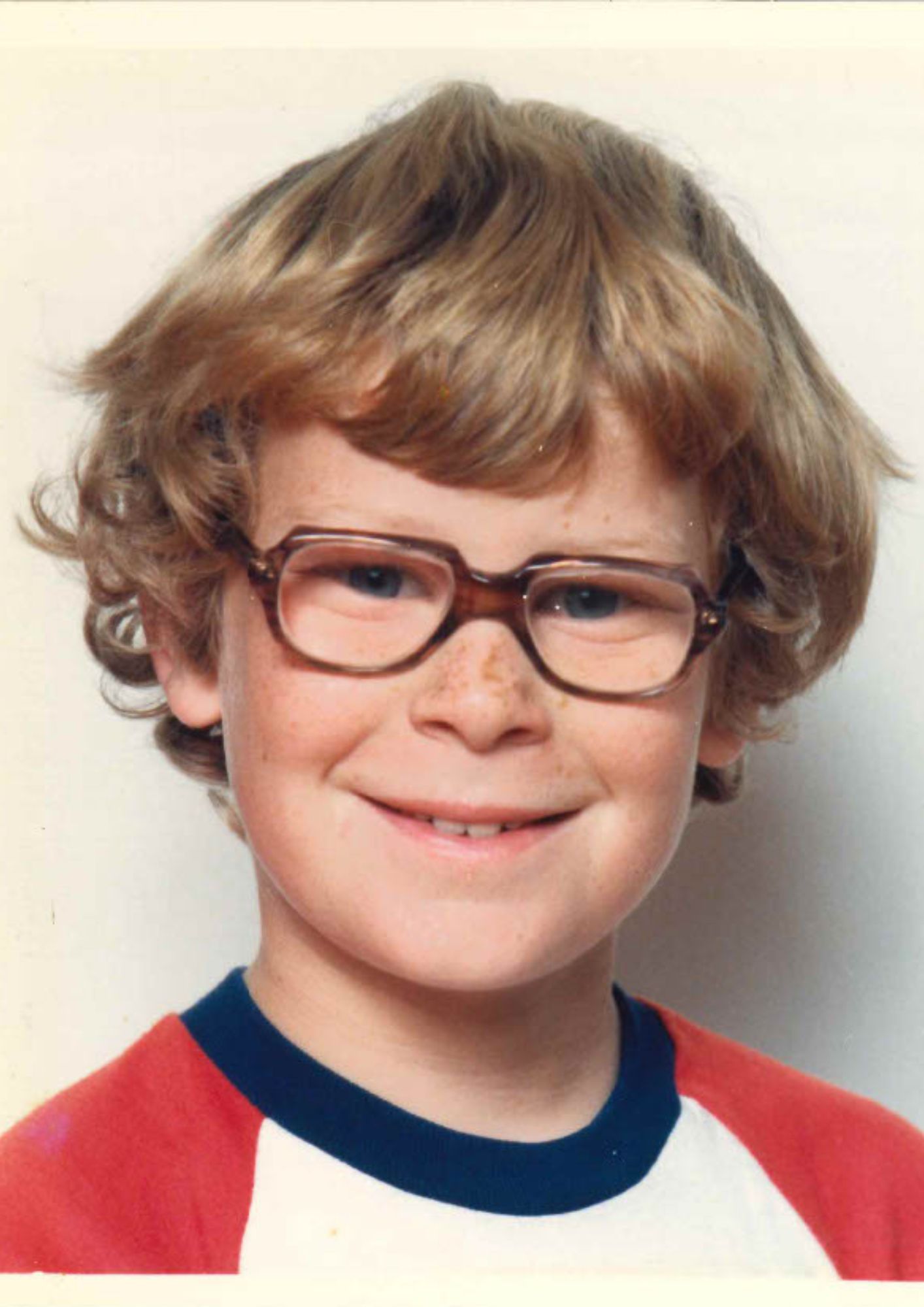 boy with dark blond hair and tortisehell glasses