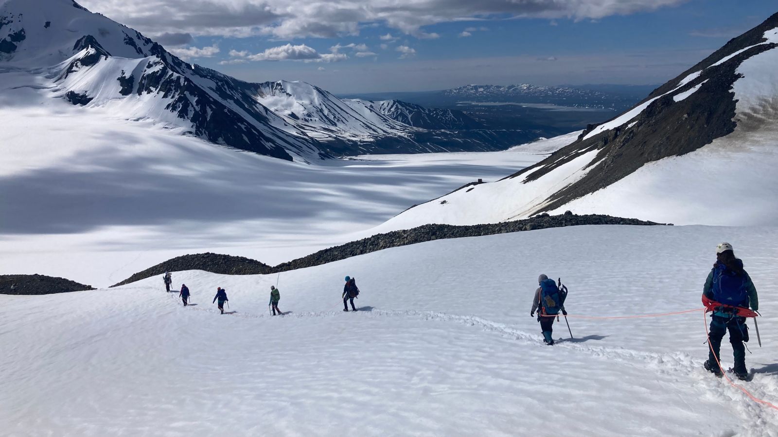 A group of mountaineers roped together crossing a glacier.