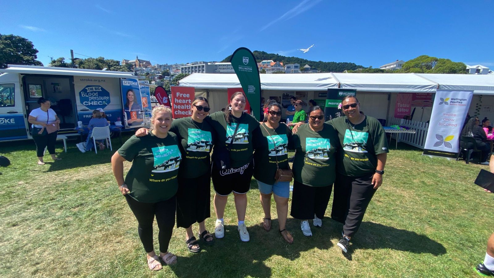 Group of people wearing Pasifika t-shirts standing outside the Pasifika marquee on a sunny day