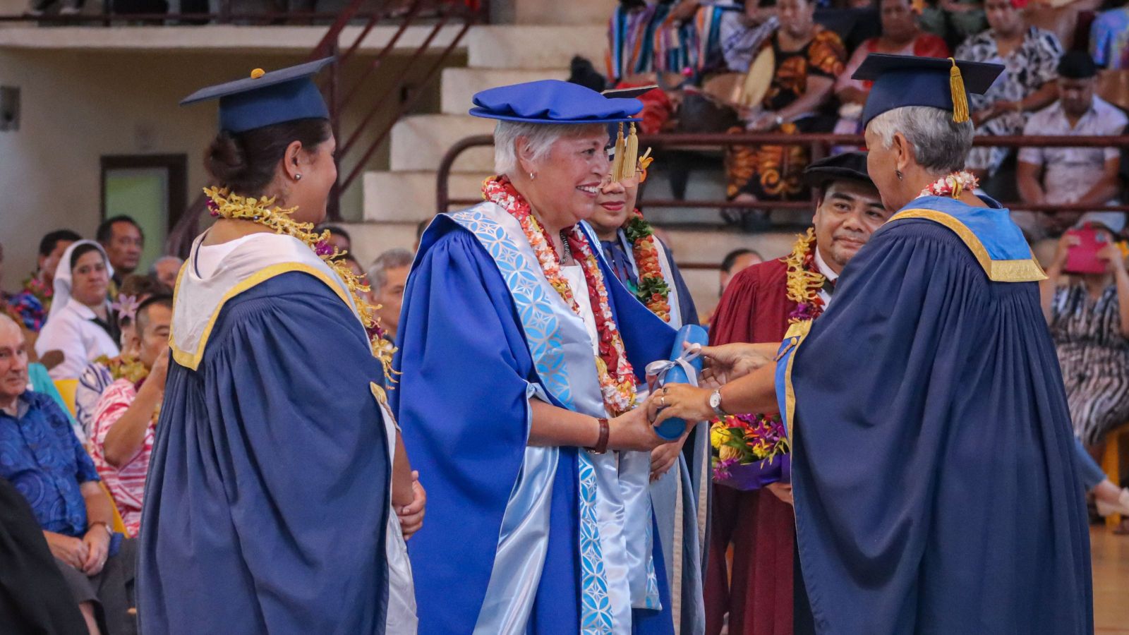 Pasifika woman in blue doctoral regalia receiving doctorate