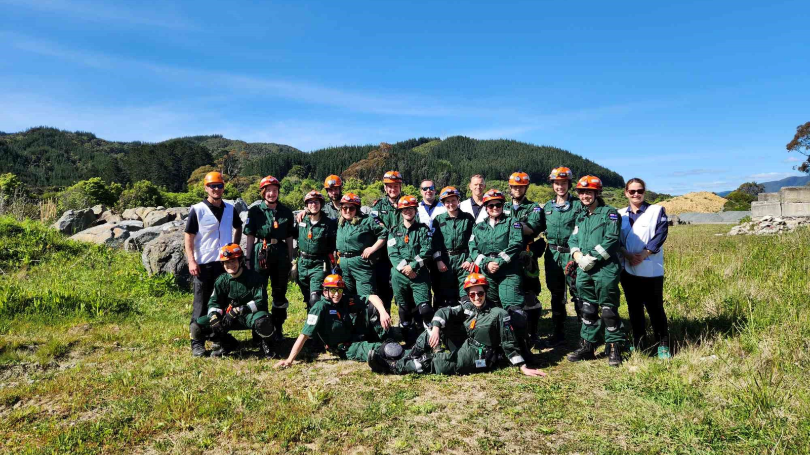 group of people wearing a green coverall uniform with solid work hats