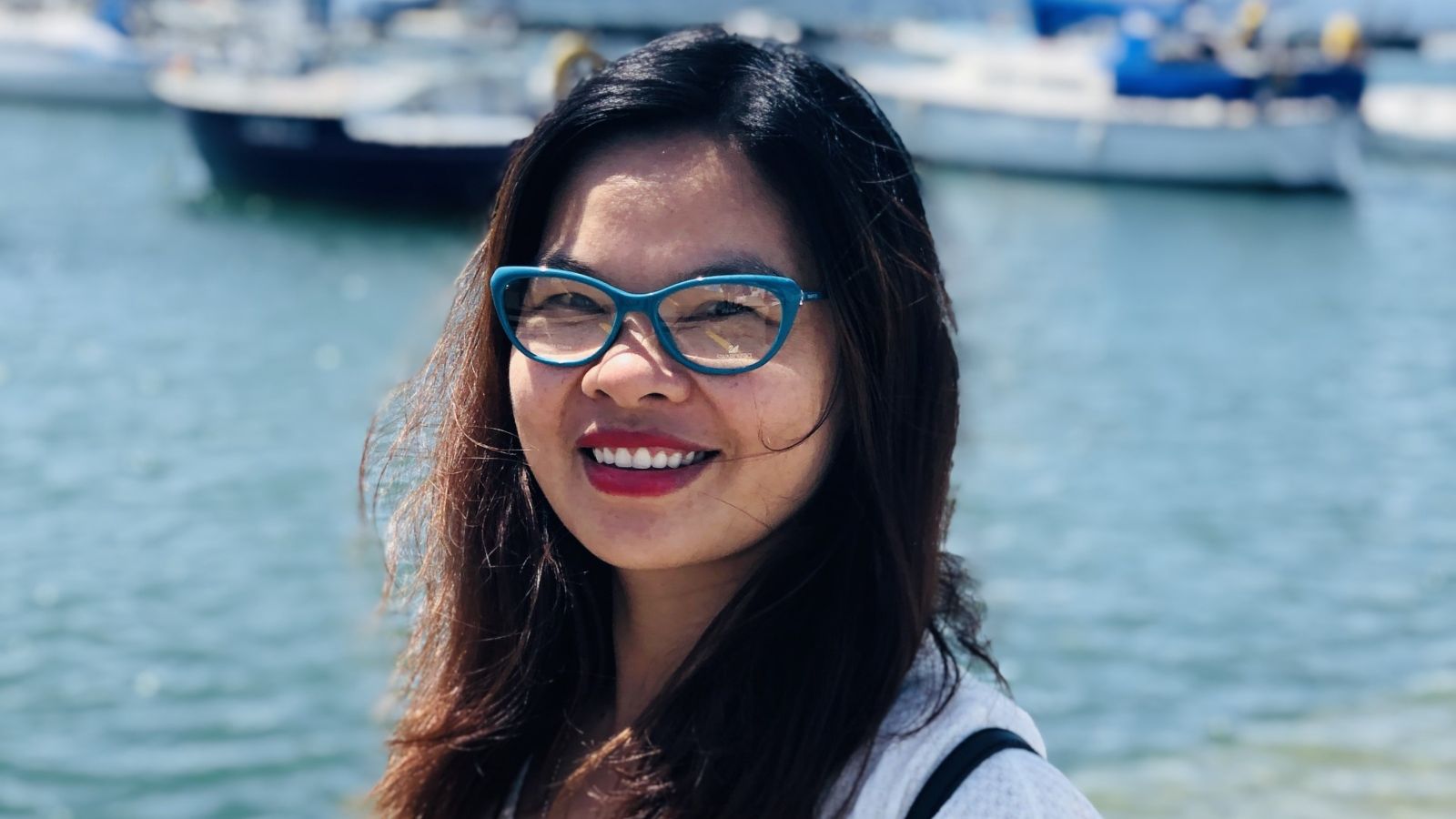 Photo of Phuong Cao standing in front of water and sail boats 