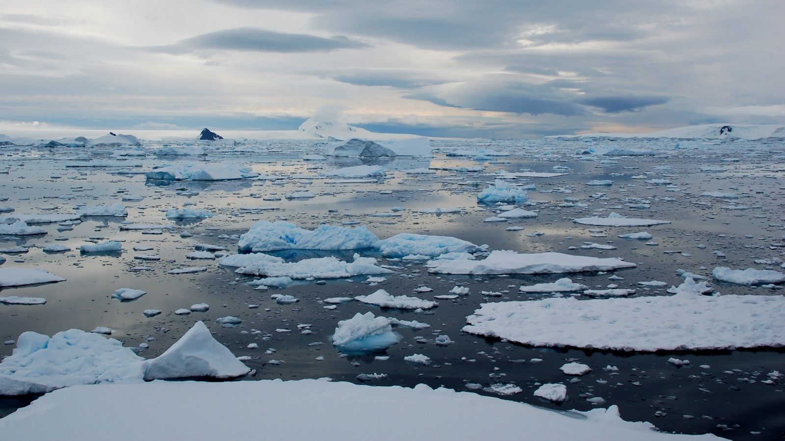 Antarctic landscape with broken ice on water in the foreground