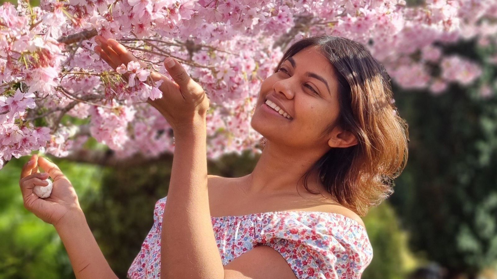 Woman smiling as she admires cherry blossom tree 
