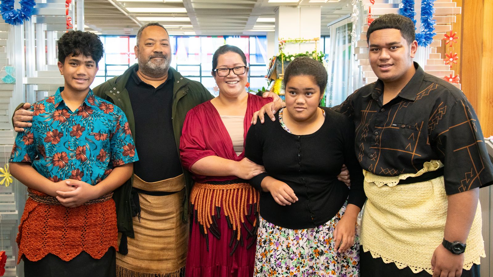 Melemo Siakumi-Mataele is standing with her husband, two sons, and daughter, in front of Wan Solwara in the University library. 