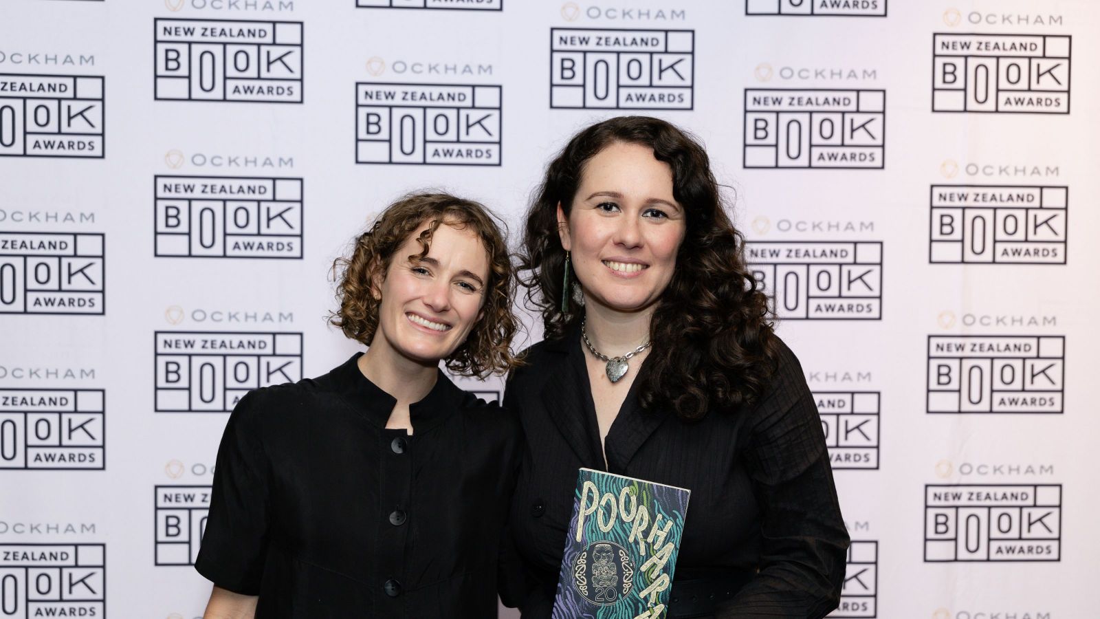 two women with curly hair, one holding a book called poorhara