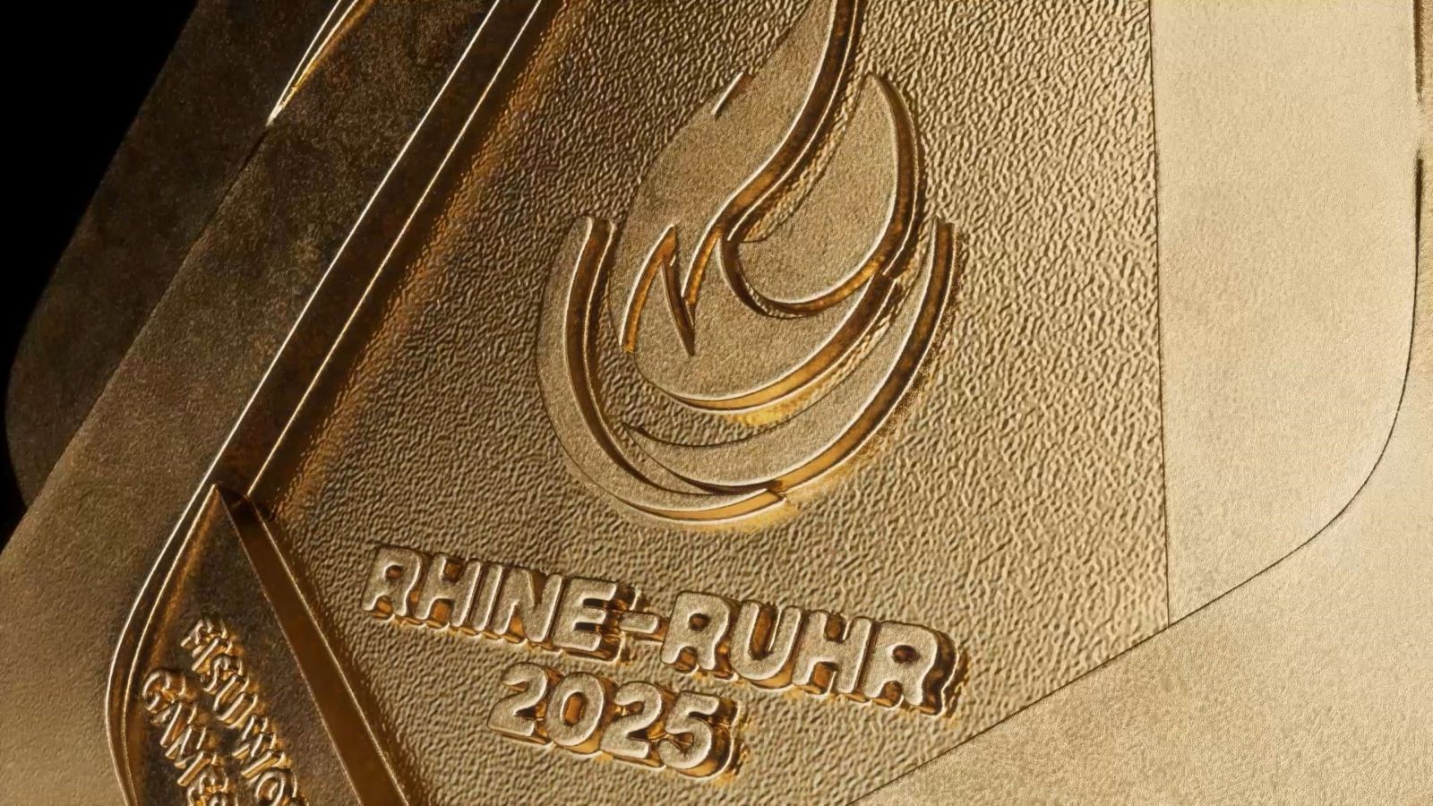 Close up of inscription on gold medal says 'Rhine-Ruhr 2025' beneath the Games' logo.