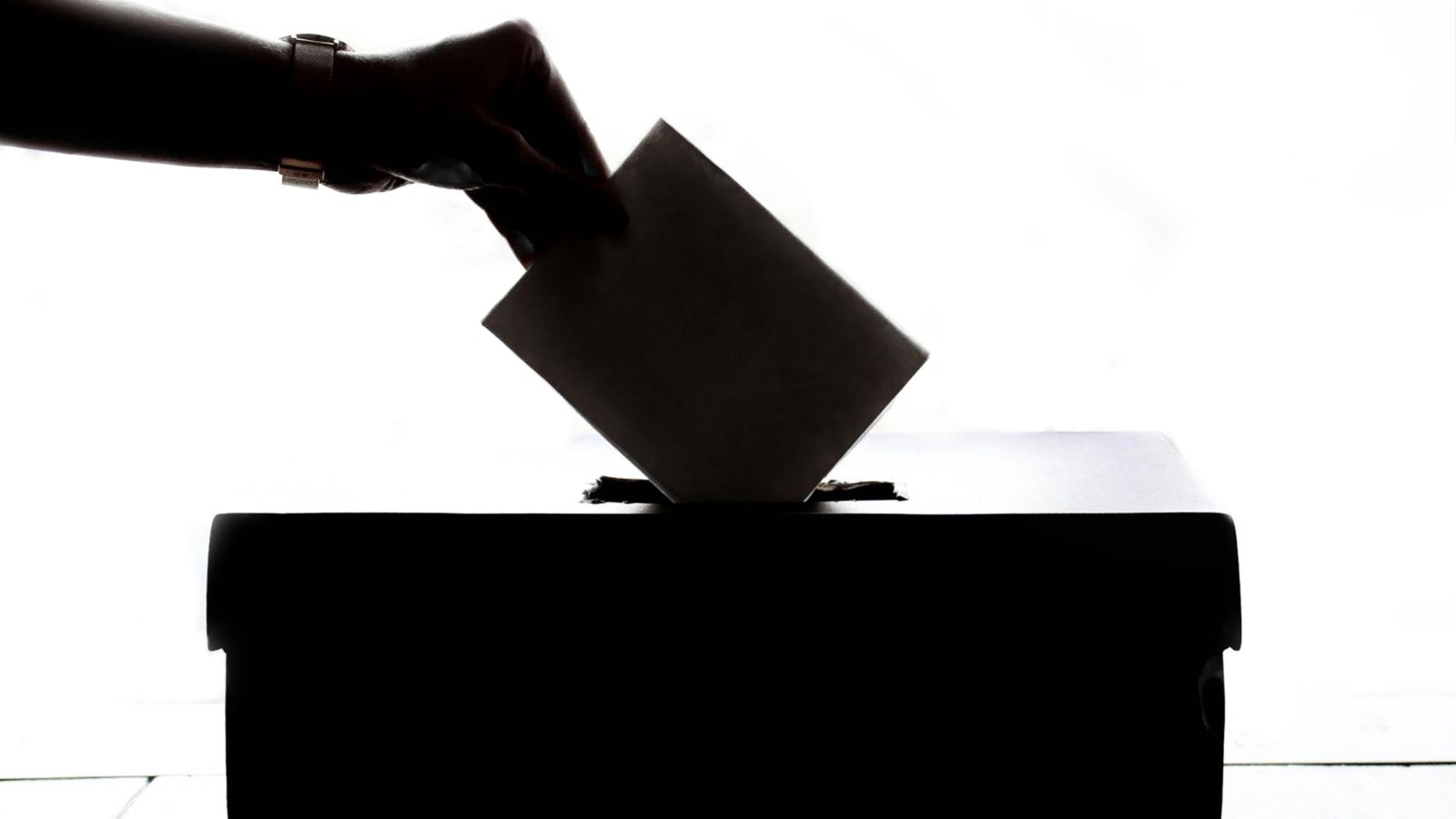 Person's hand putting voting paper in ballot box